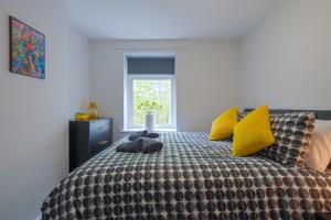 um quarto com uma cama com almofadas amarelas e uma janela em Cannock 3 bedroom house - perfect for work or leisure em Great Wyrley