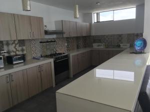 a kitchen with white counter tops and wooden cabinets at Los Libertadores Paracas Beach House in Paracas