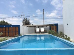 a blue swimming pool with two chairs in a house at Los Libertadores Paracas Beach House in Paracas