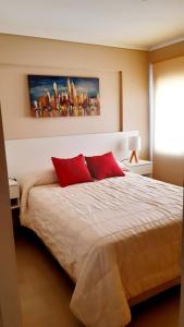 um quarto com uma cama com duas almofadas vermelhas em Departamento Temporario Zona El Tropezón Alto VillaSol em Córdoba