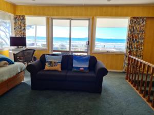 - un salon avec un canapé et une vue sur l'océan dans l'établissement Carmens Beachside Bach - Waihi Beach Bach, à Waihi Beach