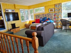 - un salon avec un canapé et une télévision dans l'établissement Carmens Beachside Bach - Waihi Beach Bach, à Waihi Beach