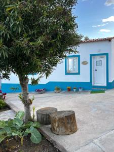 ein blaues Gebäude mit einem Baum und zwei Holzstämmen in der Unterkunft Casa da Cerca in Corte do Pinto