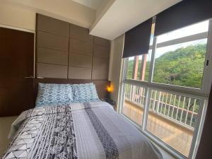 - une chambre avec un lit et une grande fenêtre dans l'établissement Miranda 311B 2br at Pico de Loro by Raquel's Place, à Nasugbu