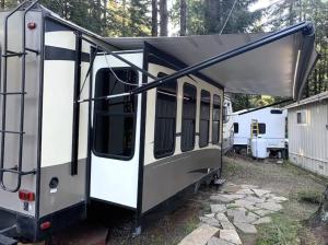 una caravana con la puerta abierta aparcada en un patio en Masoods Lodge, en Boulder Creek