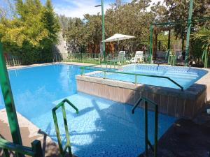 a large swimming pool with two chairs and an umbrella at Cabañas Atahualpa in Pica +15 photos