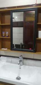 un lavandino da bagno con un grande specchio sopra di كيان a Jazan