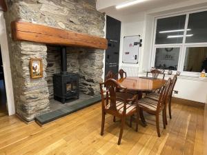 a dining room with a table and a stone fireplace at Tyn Y Fron 6 bedroom house in Betws-y-Coed Snowdonia in Betws-y-coed