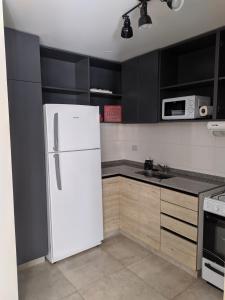 białą lodówkę w kuchni z czarnymi szafkami w obiekcie Departamento 2 dormitorios Nueva Cordoba w Córdobie
