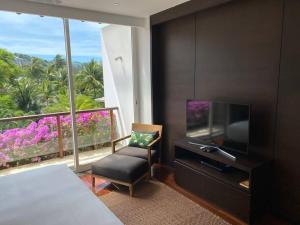 蘇林海灘的住宿－Beachfront 2 BR Luxury Condo Chava Surin，一间卧室配有电视、椅子和窗户。