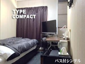 a bedroom with a bed and a desk with a computer at Business Stay in Satsumasendai