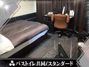 a bedroom with a bed and a desk with a computer at Business Stay in Satsumasendai