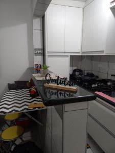 a kitchen with white cabinets and a counter with stools at Apto Top Boqueirão Praia Grande. in Praia Grande