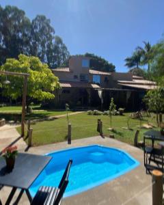 a pool with a table and chairs and a house at Pousada do Bosque in Boa Esperança