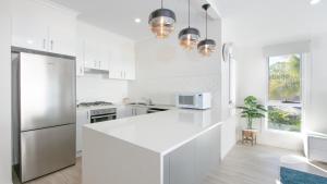 a kitchen with white cabinets and a white refrigerator at Moby Dick Waterfront Resort Motel in Yamba