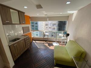 una cocina con una silla verde y una ventana grande en Apartamento com 3 dormitórios en Balneário Camboriú