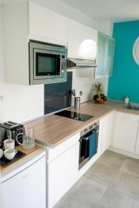 a kitchen with white cabinets and a microwave at Le Marie-Agnès Appartement neuf de Standing in Fort-de-France