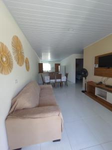 a living room with a couch and a flat screen tv at Chalés Cantinho Da Mary in São Miguel dos Milagres