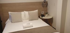 Una cama con almohadas blancas y un teléfono. en HOTEL SANTORI, en Pasto