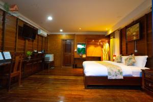 a bedroom with a bed and a desk and a television at Lodge Moni Essara Kampot in Kampot