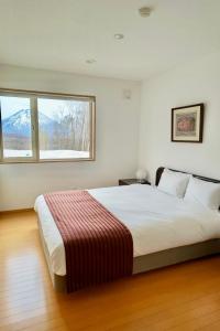 a bedroom with a large white bed with a window at Niseko HyKrots IKIGAI Village in Niseko