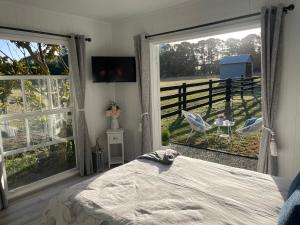 um quarto com uma cama e 2 janelas grandes em Farm Stay HARMONY Cottage at Wilindi Estate em Tyabb