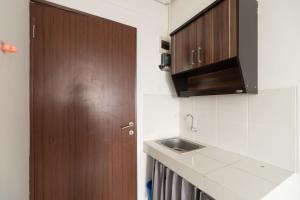 eine Küche mit einem Waschbecken und einer Holztür in der Unterkunft RedLiving Apartemen Gunung Putri - SIROOMS in Parungtandjung