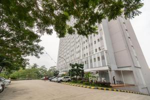 ein großes weißes Gebäude mit auf einem Parkplatz geparkten Autos in der Unterkunft RedLiving Apartemen Gunung Putri - SIROOMS in Parungtandjung