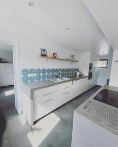 a large kitchen with white cabinets and a sink at De Veldmuis, met mooie speelhoek en speelhuis in Koksijde