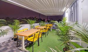 a restaurant with tables and yellow chairs and plants at Treebo Trend White Inn in Bangalore