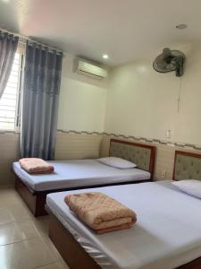 zwei Betten in einem Zimmer mit blauen Vorhängen in der Unterkunft Nhà nghỉ Hoàng Anh in Haiphong