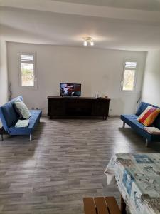 a living room with two blue couches and a television at Villaventure in Le Vauclin