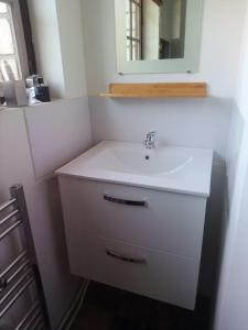 uma casa de banho com um lavatório branco e um espelho. em Source AUGER em Gruchet-le-Valasse
