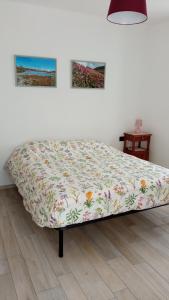 Ce lit se trouve dans un dortoir doté d'une couverture fleurie. dans l'établissement Chez Bonjour, à Villar Pellice