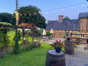 a garden with a patio and a house with lights at The Old Kitchen in Burwarton
