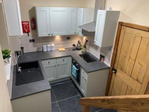 a small kitchen with white cabinets and a sink at Meg's Den in Hebden Bridge
