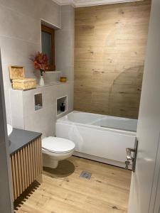 a bathroom with a white tub and a toilet at Casa de Vacanta Cris in Băile Olăneşti