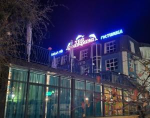 Un bâtiment avec des panneaux de néon en haut dans l'établissement Three Dolphins Hotel, à Aktau