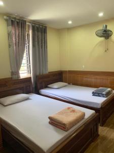 sypialnia z 2 łóżkami i oknem w obiekcie Nhà nghỉ Hoàng Anh w Hajfong