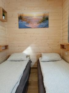 two beds in a room with wooden walls at Apartament Antonio 2 Gdańsk in Gdańsk