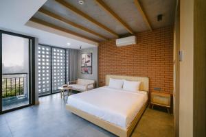 a bedroom with a white bed and a brick wall at SHI HOUSE by Haviland in Da Nang