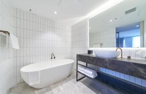 
a white bath tub sitting next to a white toilet at Pullman Adelaide in Adelaide
