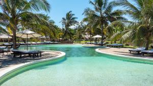 a swimming pool with chairs and palm trees in a resort at Ocean Beach Resort & SPA in Malindi