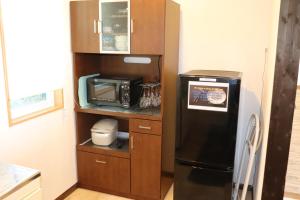 eine Küche mit einem schwarzen Kühlschrank und einer Mikrowelle in der Unterkunft コテージトガワ＜Cottage TOGAWA＞ in Fujikawaguchiko