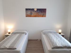 dwa łóżka w pokoju z obrazem na ścianie w obiekcie Eisenstadt Apartments w mieście Eisenstadt