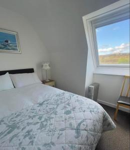 a bedroom with a bed and a large window at Taigh Iain Mhòir in Skeabost