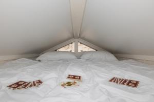 een wit bed met 2 kussens en een raam bij Slaapstrandhuisje 182, Dishoek in Dishoek