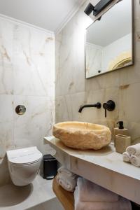 a bathroom with a sink and a toilet and a mirror at Porto Del Colombo Traditional Boutique Hotel in Chania