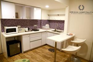 a kitchen with white cabinets and a microwave and a table at Rajhans Belliza Luxurious Studio Apartment in Surat