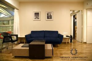 a living room with a blue couch and a table at Rajhans Belliza Luxurious Studio Apartment in Surat